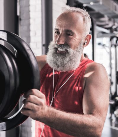 Älterer Mann mit Hantelscheibe im Fitness-Studio Bremen